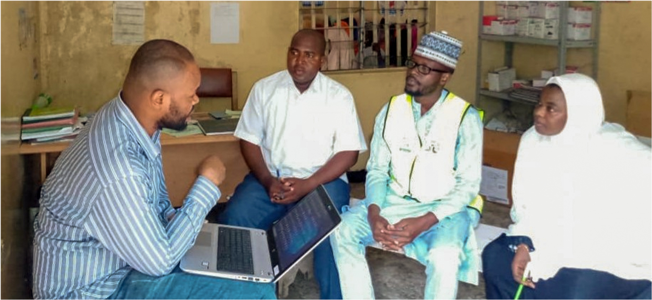 A man with a laptop speaks to three people.