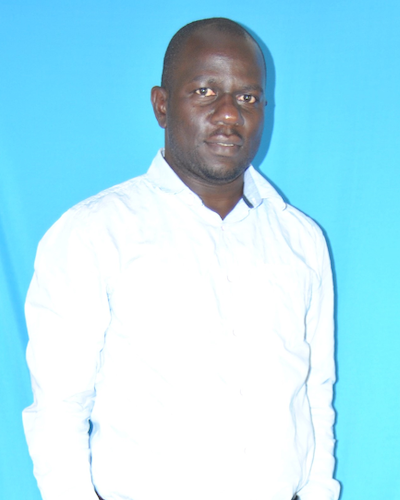 A man wears a white button down shirt and stands in front of a light blue background.